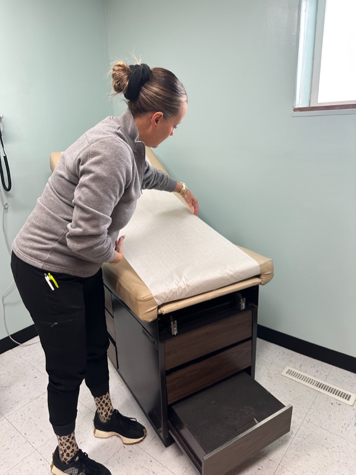A nurse preparing an exam room for a patient